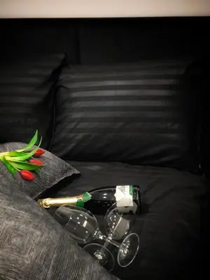 a tray with wine glasses and a bottle and flowers on a bed at DOMINO apartamentai, SELF CHECK-IN in Panevėžys