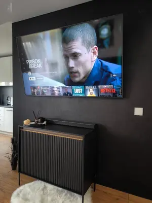 a flat screen tv on a black wall at DOMINO apartamentai, SELF CHECK-IN in Panevėžys