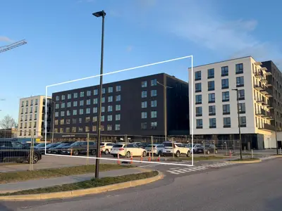 a large building with cars parked in a parking lot at Ozas Cozy Studio apartment in Vilnius