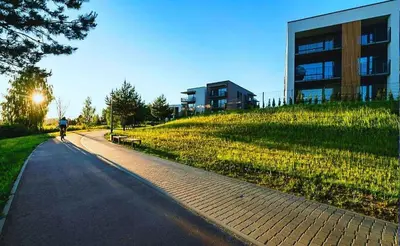 a person riding a bike down a road next to a building at Apartamentai prie ežero in Vilnius