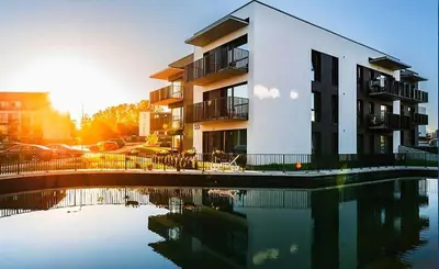 a building with a reflection in a body of water at Apartamentai prie ežero in Vilnius