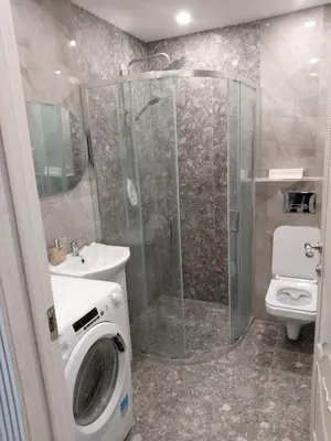 a bathroom with a shower and a washing machine at Apartamentai prie ežero in Vilnius