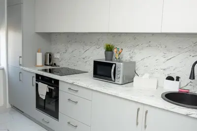 a white kitchen with a microwave and a sink at El Roi Home's in Vilnius