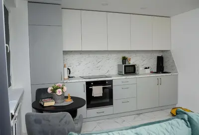 a kitchen with white cabinets and a table with a microwave at El Roi Home's in Vilnius