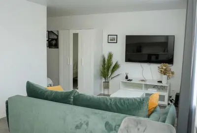 a living room with a green couch and a tv at El Roi Home's in Vilnius