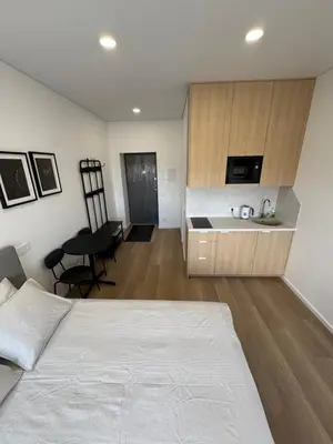a bedroom with a white bed and a kitchen at New Airport Apartment in VNO