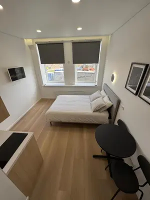 a small bedroom with a bed and a table and chairs at New Airport Apartment in VNO