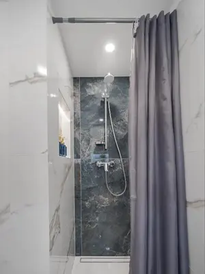 a shower with a gray shower curtain in a bathroom at 60 Loft in Vilnius