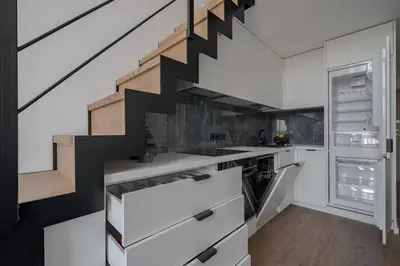 a kitchen with white cabinets and a black staircase at 60 Loft in Vilnius