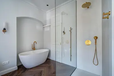 a white bathroom with a tub and a glass shower at New! Luxury Old town apartment in Vilnius