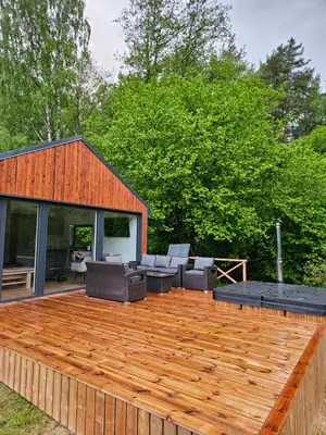 a wooden deck with chairs and a house at Pasienio Krantas in Velūnai