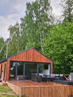 a house with a large deck with furniture on it at Pasienio Krantas in Velūnai