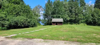 a field with a small building in the middle of it at Pasienio Krantas in Velūnai