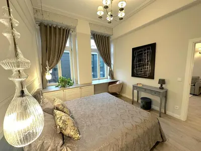 a bedroom with a bed and a table and windows at Apartamentai Bazilijonai in Vilnius
