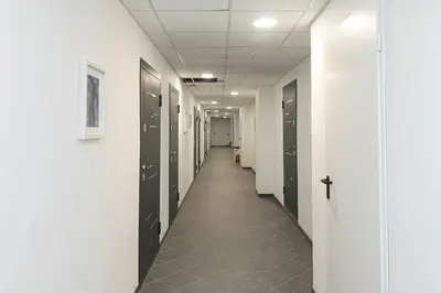 a hallway with black lockers and a hallway with a row of doors at ShortStopStudent in Vilnius