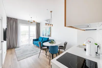 a kitchen and living room with a table and chairs at City Center Apartamentai Šatrijos g in Vilnius