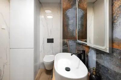 a bathroom with a white sink and a toilet at City Center Apartamentai Šatrijos g in Vilnius