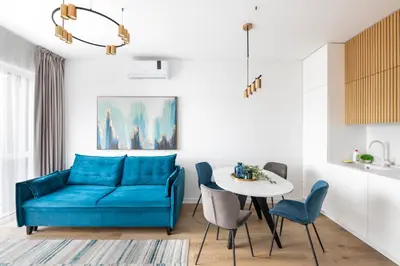 a living room with a blue couch and a table at City Center Apartamentai Šatrijos g in Vilnius