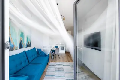 a living room with a blue couch and a table at City Center Apartamentai Šatrijos g in Vilnius