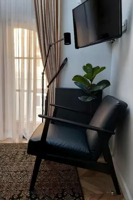 a black leather chair in a living room with a tv at Elumen Studio Apartment I near Cathedral & Bernardine Park in Vilnius