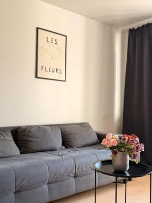 a living room with a couch and a table with flowers at Apartamentai Jonavoje #2 in Jonava