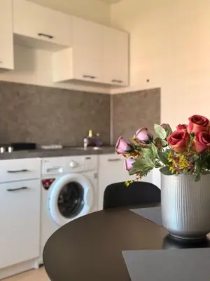 a kitchen with a table with a vase of roses at Apartamentai Jonavoje #2 in Jonava