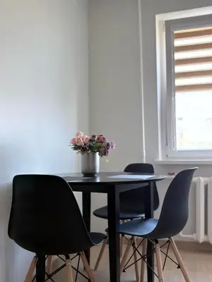 a table with three chairs and a vase of flowers on it at Apartamentai Jonavoje #2 in Jonava