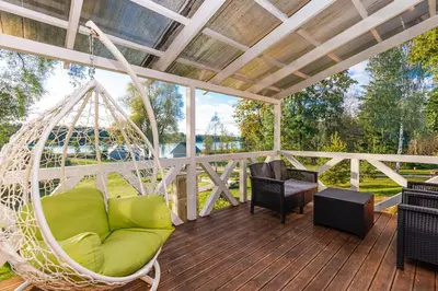 a porch with a hammock and chairs on a deck at Namas su vaizdu į ežerą 