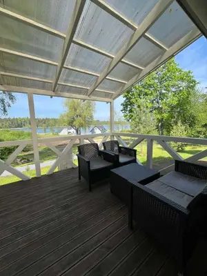 a porch with benches and tables on a deck at Namas su vaizdu į ežerą 