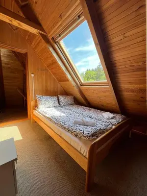 a bed in a wooden room with a window at Namas su vaizdu į ežerą 