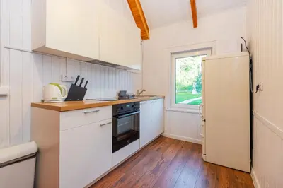 a small kitchen with white cabinets and a window at Namas su vaizdu į ežerą 