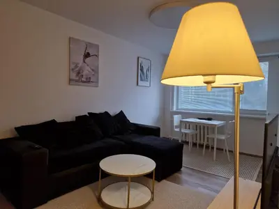 a living room with a black couch and a yellow lamp at Close to Park in Kaunas