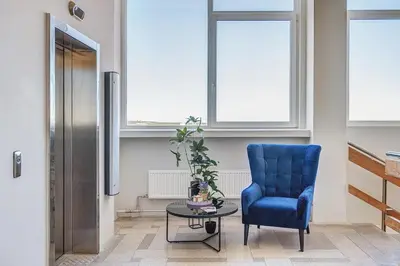a blue chair and a table in a room with windows at Modern Studio near the city center in Vilnius
