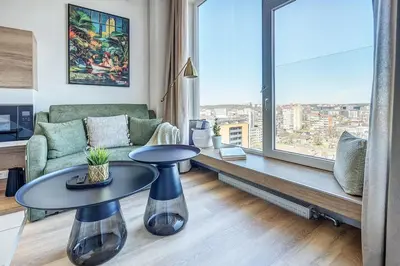 a living room with a couch and a table and a large window at Modern Studio near the city center in Vilnius