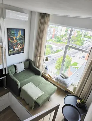 a living room with a couch and a large window at Modern Studio near the city center in Vilnius