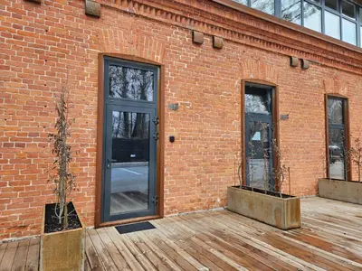 a brick building with two doors and a wooden deck at Loft in Freda in Kaunas