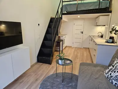 a living room with a couch and a kitchen and a staircase at Loft in Freda in Kaunas