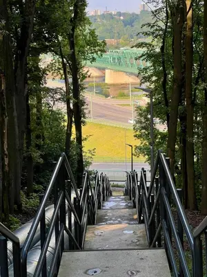 a wooden bridge in a park with trees and a road at Loft in Freda in Kaunas