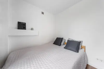 a white bedroom with a bed with blue pillows at Bright, cozy apartment 5 min walk to Old town in Vilnius