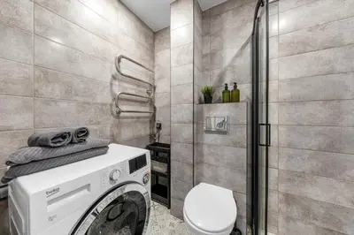 a bathroom with a washing machine and a toilet at Bright, cozy apartment 5 min walk to Old town in Vilnius