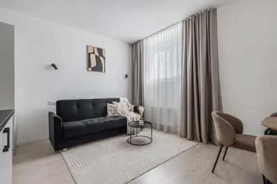 a living room with a black couch and a table at Fox Rock Studio - Self check in in Vilnius