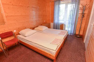a bedroom with a bed and a chair and a window at Nakvynė prie ežero Akmenėlis in Dyviliškiai