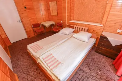 a bedroom with a large bed and a table and chairs at Nakvynė prie ežero Akmenėlis in Dyviliškiai