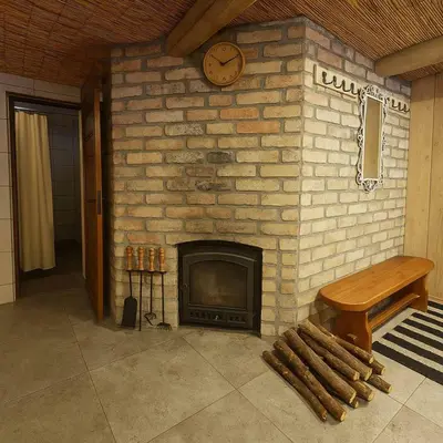 a brick fireplace with a clock and a bench at Apartamentai in Veisiejai