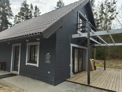 a black house with a balcony on a deck at Apartamentai in Veisiejai