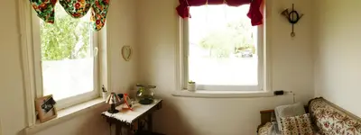 a living room with two windows and a couch at Namelis 1954 in Švenčionėliai