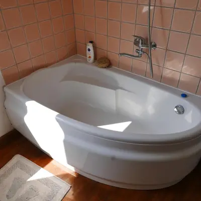 a white bath tub in a bathroom with a tile wall at Namelis 1954 in Švenčionėliai