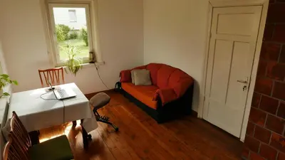 a living room with a red couch and a table at Namelis 1954 in Švenčionėliai