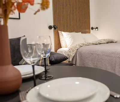 a table with two wine glasses and a bed at Lukiškės Central Apartment - Self Check-in and Parking Option in Vilnius