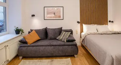 a bedroom with a bed and a couch with pillows at Lukiškės Central Apartment - Self Check-in and Parking Option in Vilnius